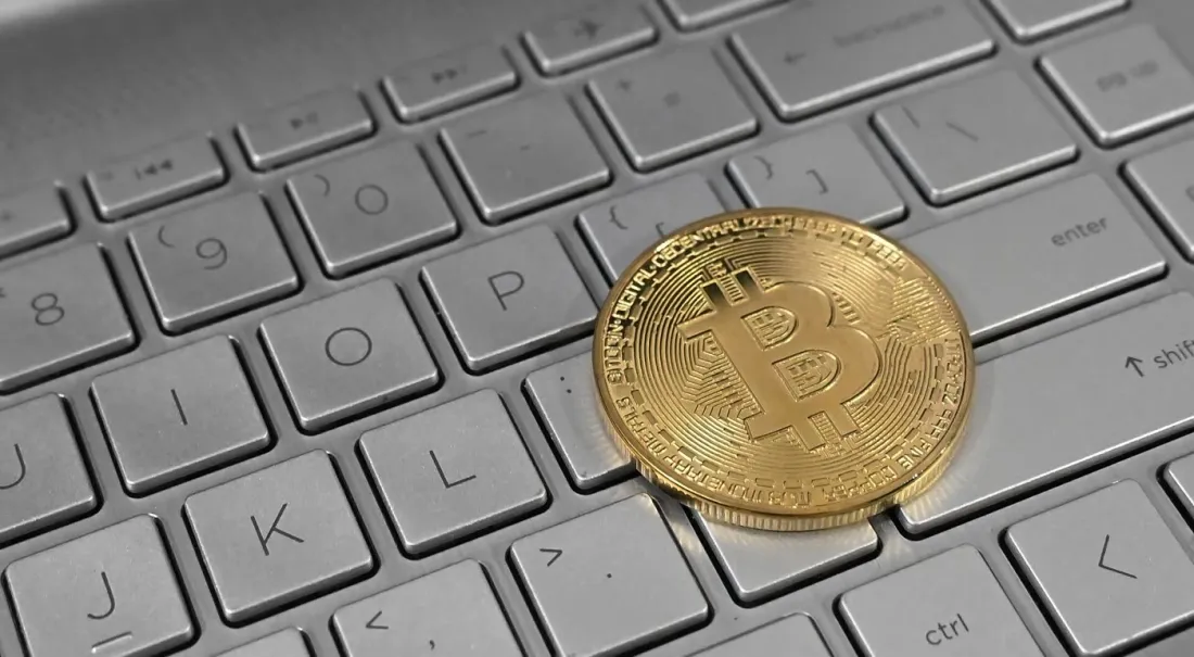 A gold Bitcoin coin on a laptop keyboard